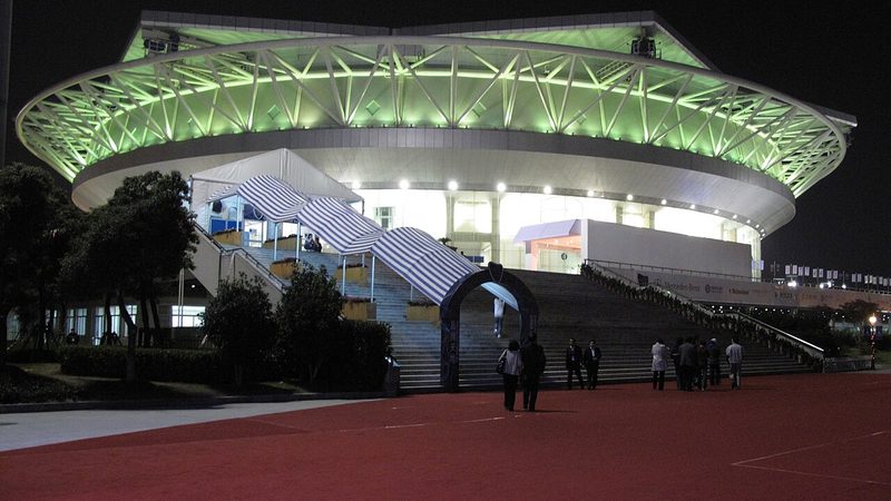 Exterior of Qizhong Stadium in Shanghai, illuminated at night.